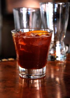 a close up of a drink on a table with glasses in the backgroud