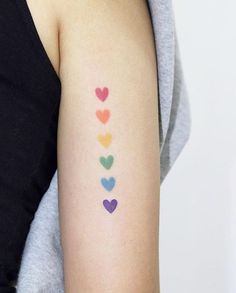 a woman's arm with colorful hearts painted on the back of her left arm