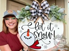 a woman holding up a snowman sign with the words let it snow on it