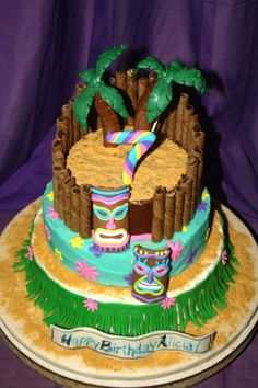 a birthday cake decorated with palm trees and beach items on a purple tablecloth background