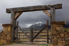 an old wooden gate in the middle of nowhere with mountains in the background, on a cloudy day