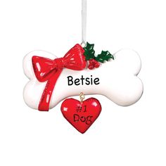 a dog bone ornament with a red bow and holly on it's side