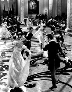 a black and white photo of people in formal dress dancing on the dancefloor