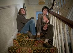 two people sitting on the stairs of a house