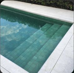 an empty swimming pool with tiled steps leading up to it