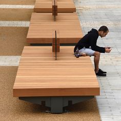 a man sitting on top of a wooden bench next to another bench with benches behind him