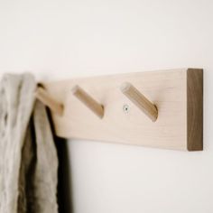 the coat rack is made from wood and has two hooks on each side that hold clothes