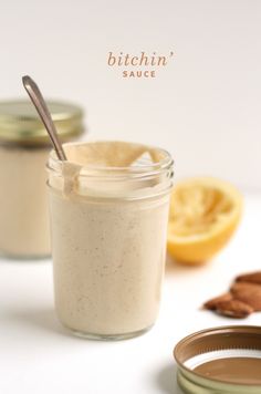 two jars filled with food sitting on top of a white table next to sliced lemons