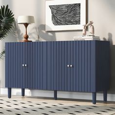 a blue sideboard with two doors and three legs in a room next to a lamp