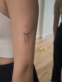 a woman's arm with a tattoo that has a small bow on the side