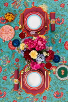 the table is set with colorful flowers and plates