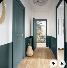 an empty hallway with green doors and wooden floors