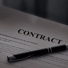 a pen sitting on top of a paper with the word contract written in it's center