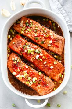 baked salmon fillets in a white casserole dish with garnishes