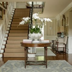 a table with flowers on it in the middle of a room next to some stairs