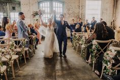 a bride and groom walking down the aisle after their wedding ceremony in an industrial building