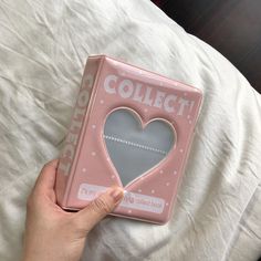 a person holding a pink heart shaped object in front of a white sheet with the word collect on it