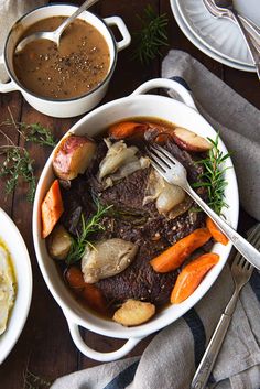 a bowl of stew with carrots, potatoes and gravy on the side