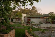 the house is surrounded by greenery and rocks in front of it's windows