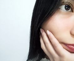 a close up of a person holding their hand to her face and looking at the camera