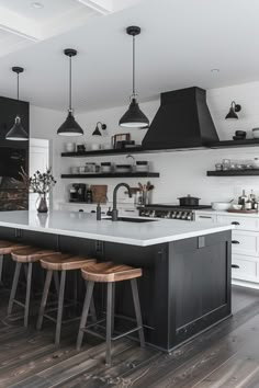 a kitchen with black and white cabinets, wooden stools and an island countertop