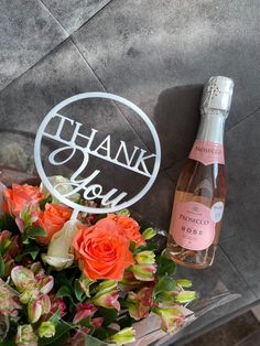 a bouquet of flowers and a bottle of wine are sitting next to a sign that says thank you