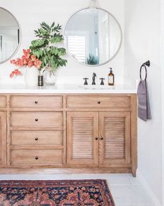 a bathroom with two round mirrors on the wall and a rug in front of it