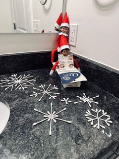 an elf is sitting on top of a box with snowflakes in the bathroom