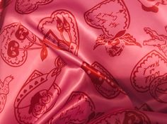 a pink background with red and white designs on it, including an eyeliner brush