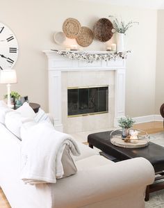 a living room filled with furniture and a clock on the wall above the fire place