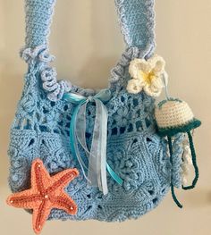 a blue crocheted purse with two starfish decorations hanging from it's side