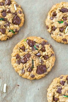 four cookies with chocolate chips and green onions on a piece of parchment paper, ready to be eaten