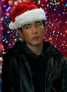 a young man wearing a santa hat in front of colorful boket background with lights