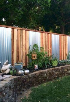 an outdoor garden area with various plants and pots on the ground near a wooden fence