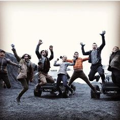 a group of people jumping in the air on top of a truck with their hands up