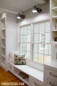 a window seat in the corner of a room with bookshelves and pillows on it