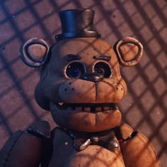 a creepy looking teddy bear with a top hat and bow tie, standing in front of a chain link fence