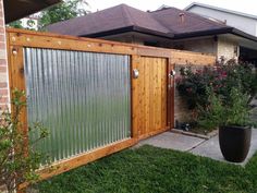 a wooden fence in front of a house with a potted plant next to it