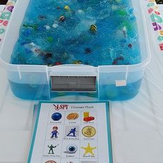 a plastic container filled with blue liquid on top of a table next to a sign