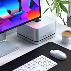 a computer monitor sitting on top of a desk next to a keyboard and mouse with a cup of coffee in front of it