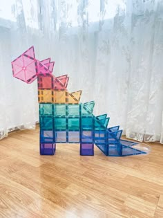 three colorful glass sculptures sitting on top of a hard wood floor next to a window