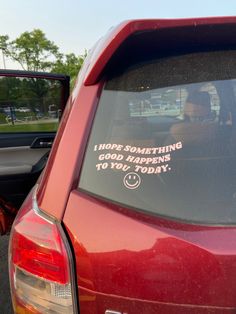 a red car parked in a parking lot with a sticker on the back window