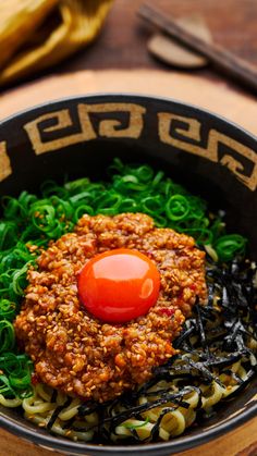 a black bowl filled with noodles and sauce