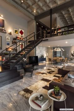 a living room filled with lots of furniture and a staircase leading up to the second floor