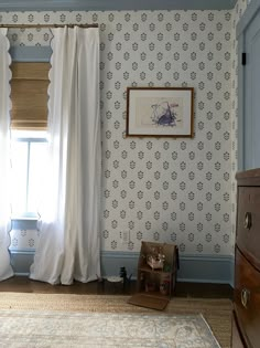 a bedroom with blue walls and white curtains on the window sill, next to a dresser