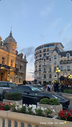 several cars parked in front of buildings on a city street at dusk with people walking by