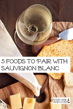 a wooden cutting board topped with cheese and crackers next to a glass of wine