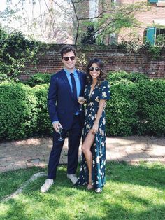 a man in a suit and tie standing next to a woman wearing a floral dress