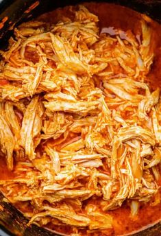 shredded chicken in a slow cooker being cooked