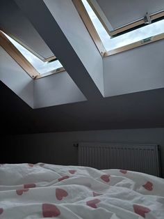 a bedroom with two skylights above the bed and pink hearts on the comforter